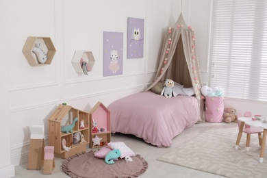 Photo of Cute child's room interior with toys and modern furniture