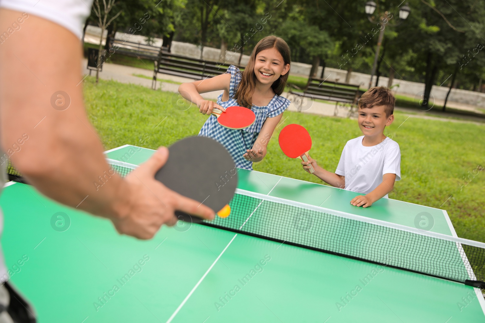 Photo of Man with children playing ping pong in park