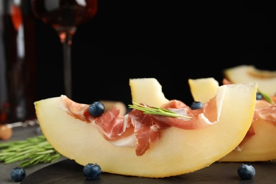 Photo of Melon with prosciutto, blueberries and rosemary on table