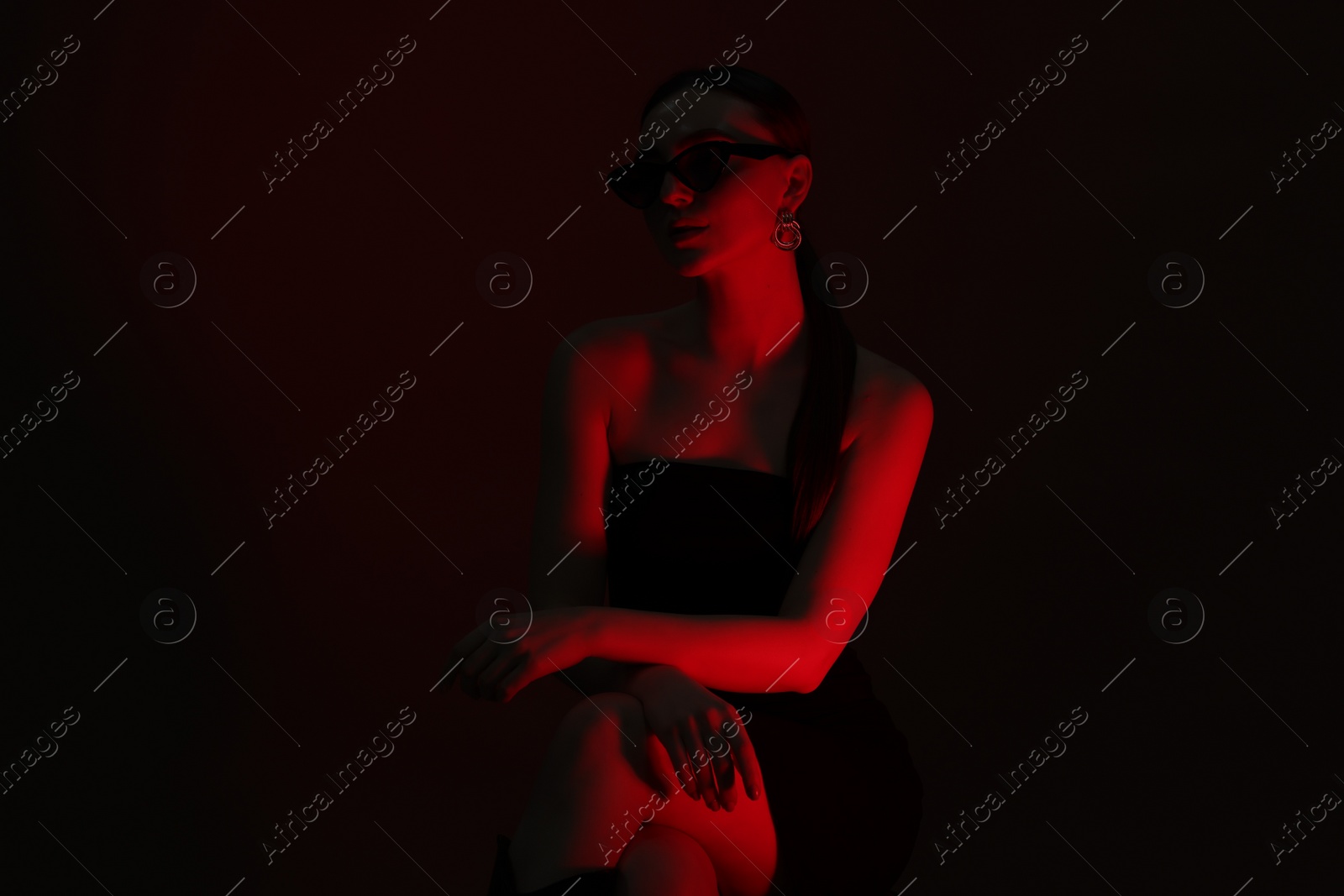 Photo of Portrait of beautiful young woman in sunglasses on dark background with neon lights