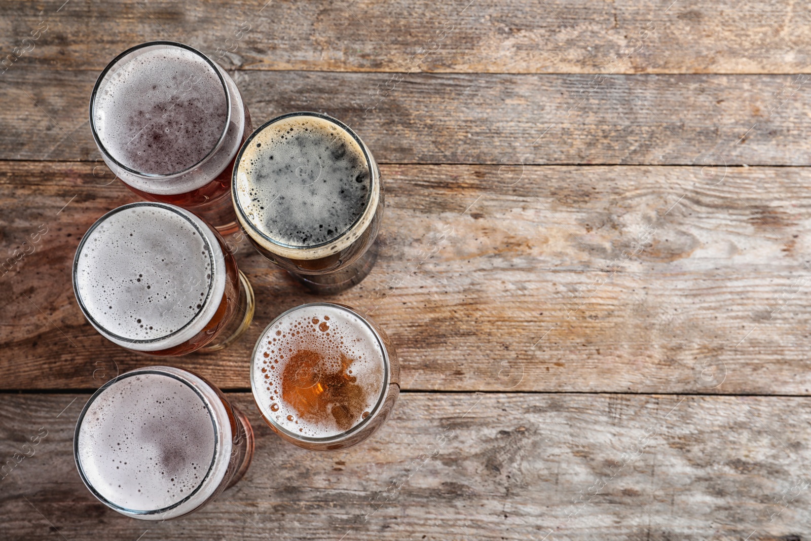 Photo of Glasses with different types of cold tasty beer on wooden background