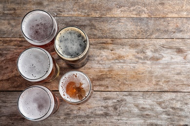 Photo of Glasses with different types of cold tasty beer on wooden background