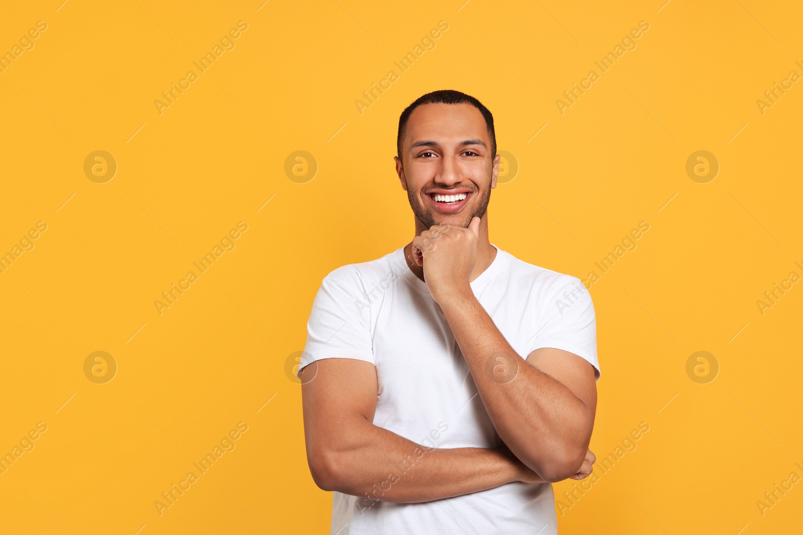 Photo of Portrait of happy African American man on orange background. Space for text