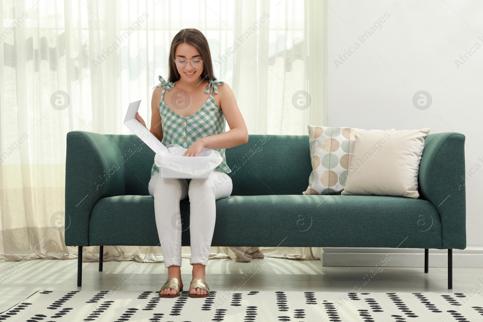 Photo of Happy young woman opening parcel at home. Internet shopping