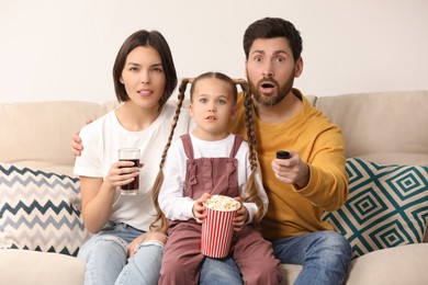 Photo of Family watching TV with popcorn on sofa indoors