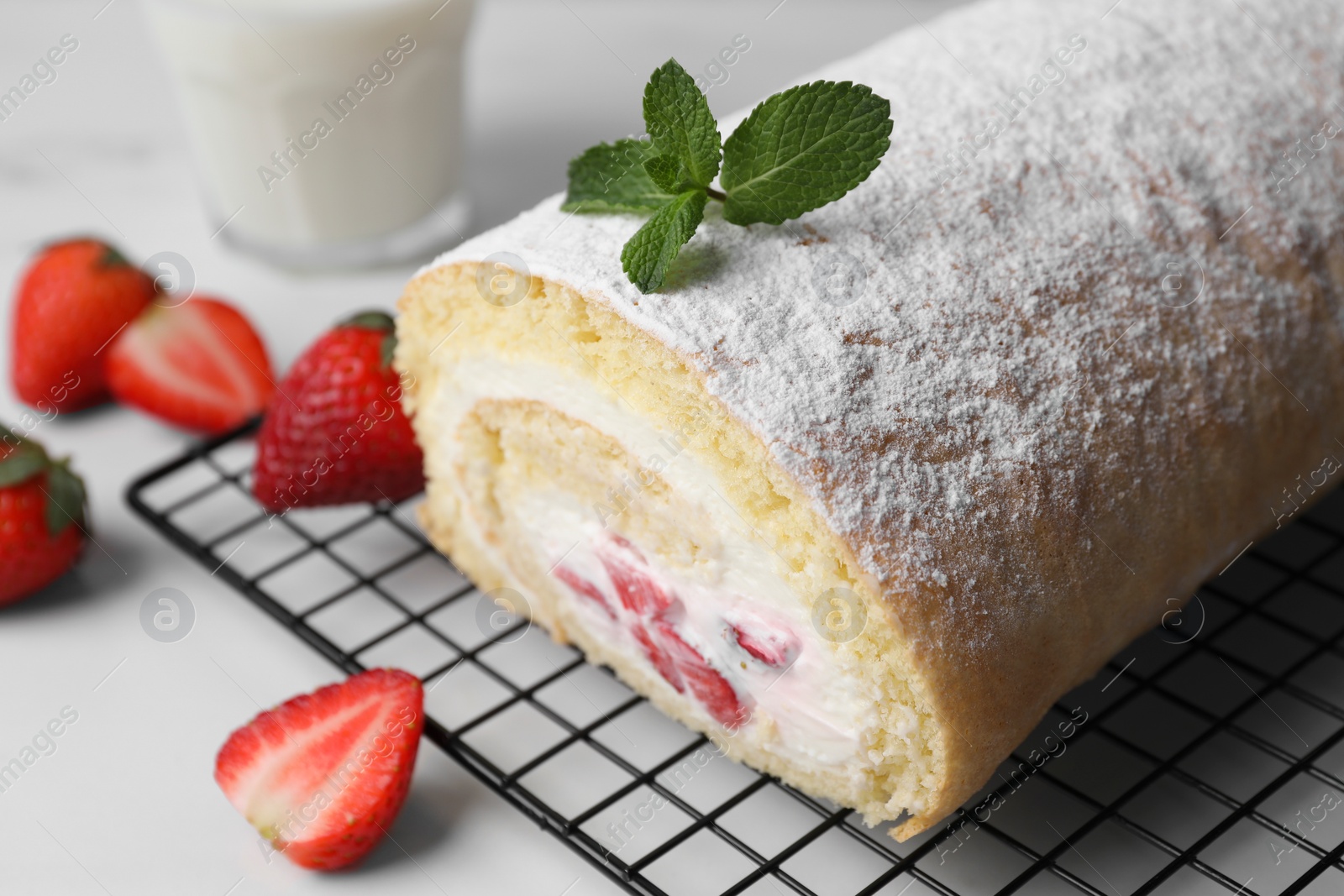 Photo of Delicious sponge cake roll with strawberries and cream on white table, closeup