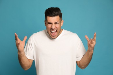 Photo of Angry man on turquoise background. Hate concept