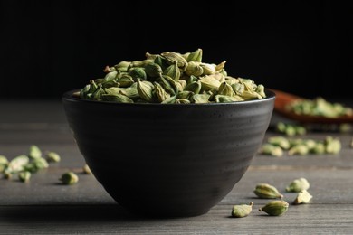 Bowl of dry cardamom pods on wooden table