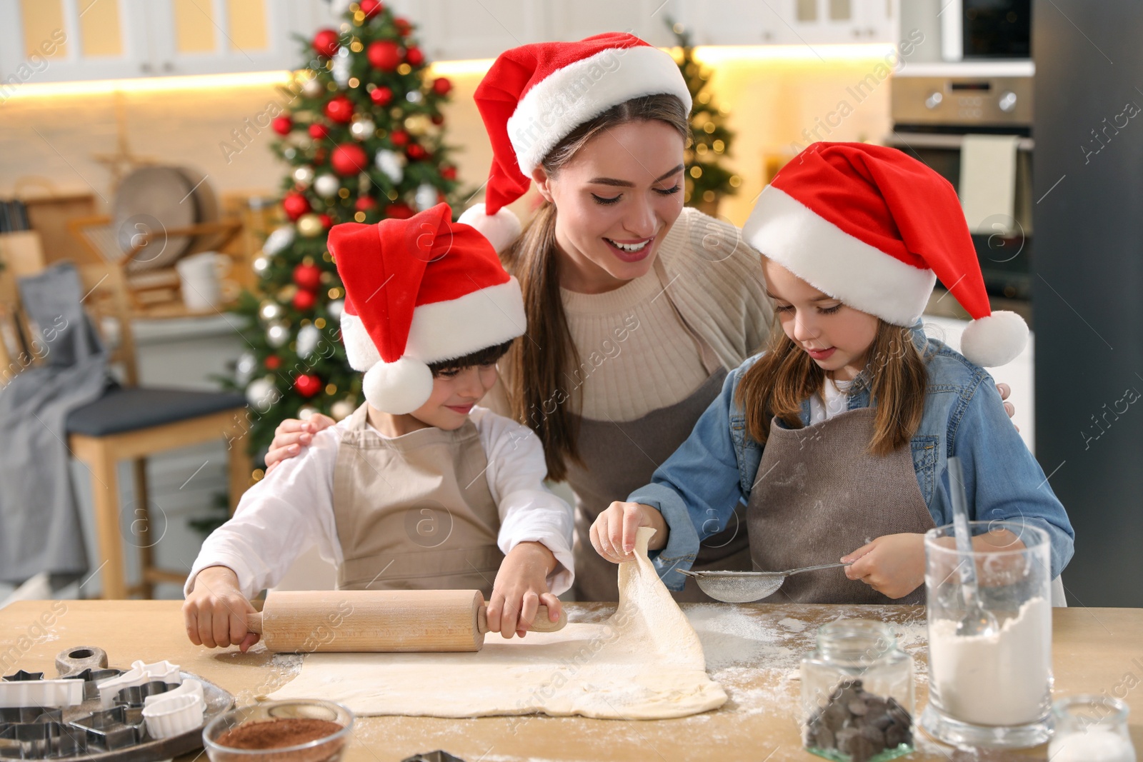 Photo of Mother with her cute little children making dough for Christmas cookies in kitchen