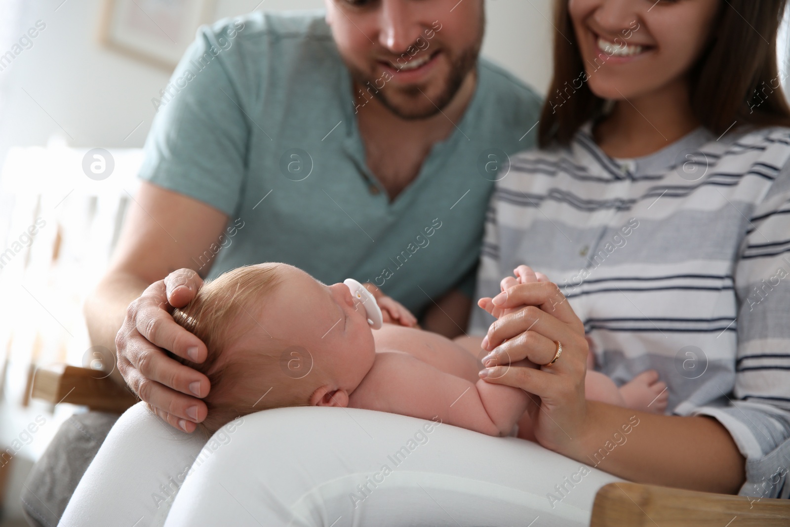 Photo of Happy couple with their newborn baby at home, closeup