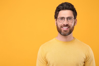 Photo of Portrait of handsome man in glasses on orange background, space for text