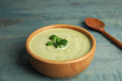 Photo of Delicious broccoli cream soup served on blue wooden table