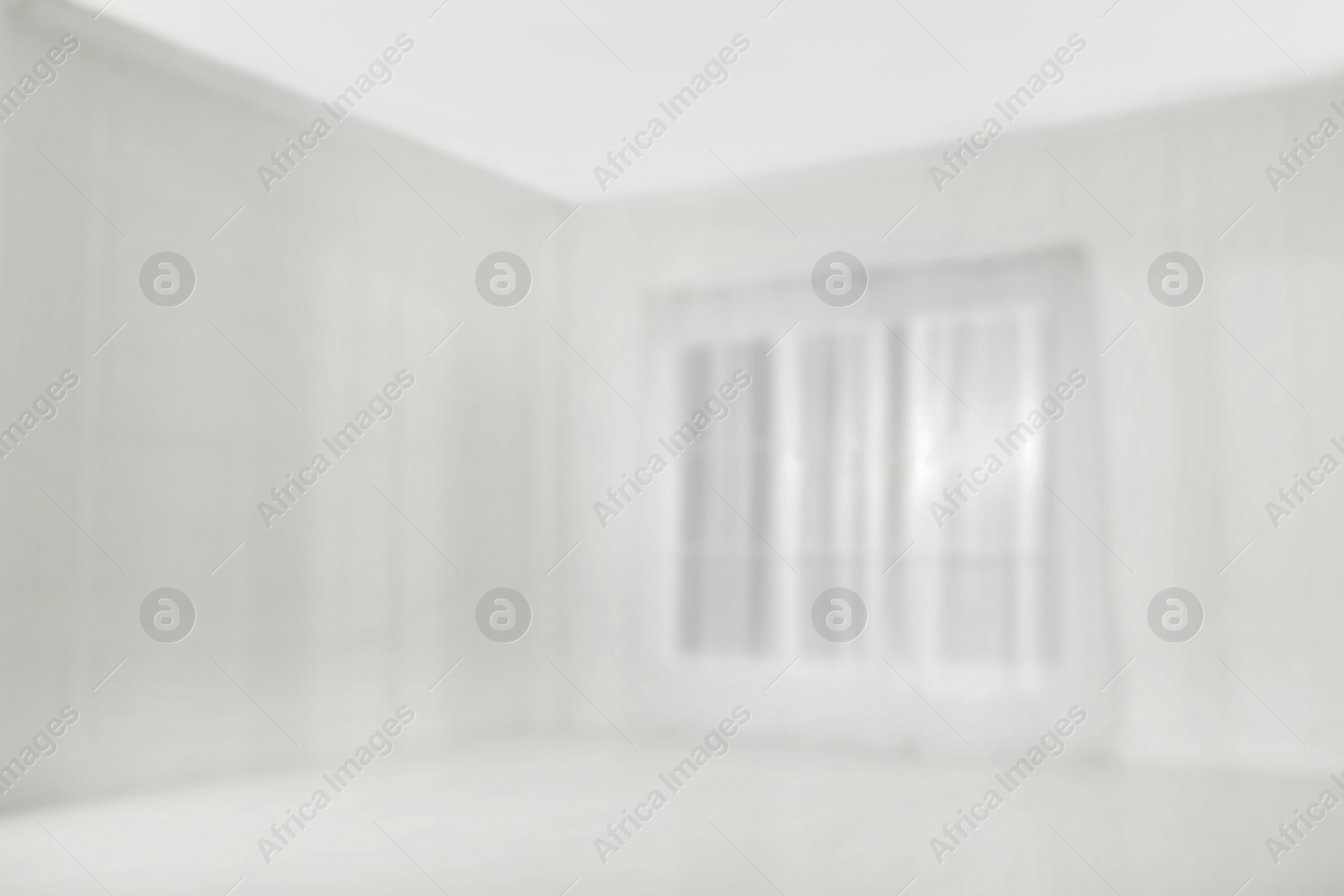 Photo of Empty room with white walls and large window, blurred view