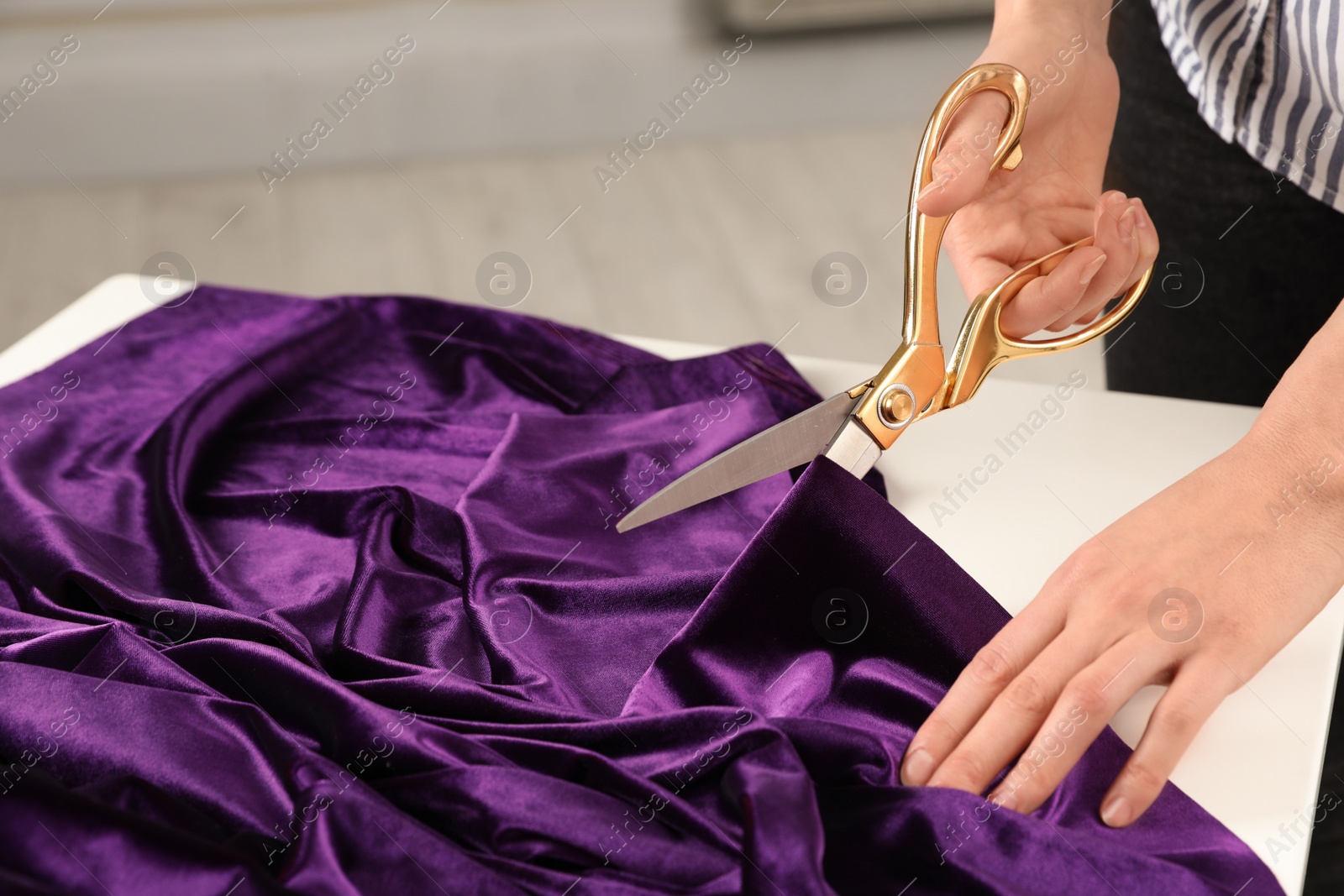 Photo of Woman cutting fabric with sharp scissors at table indoors, closeup. Space for text