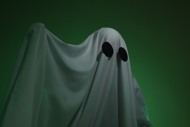 Photo of Creepy ghost. Woman covered with sheet on dark green background