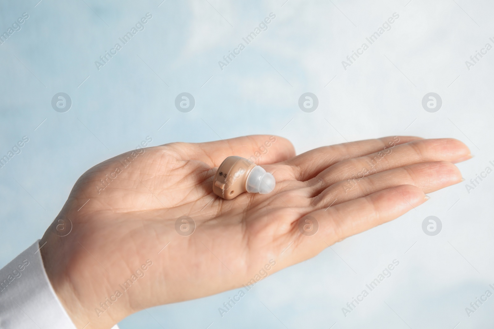 Photo of Woman with hearing aid on color background, closeup