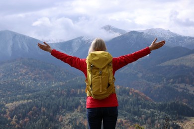 Photo of Happy woman with backpack admiring mountain landscape, back view. Feeling freedom