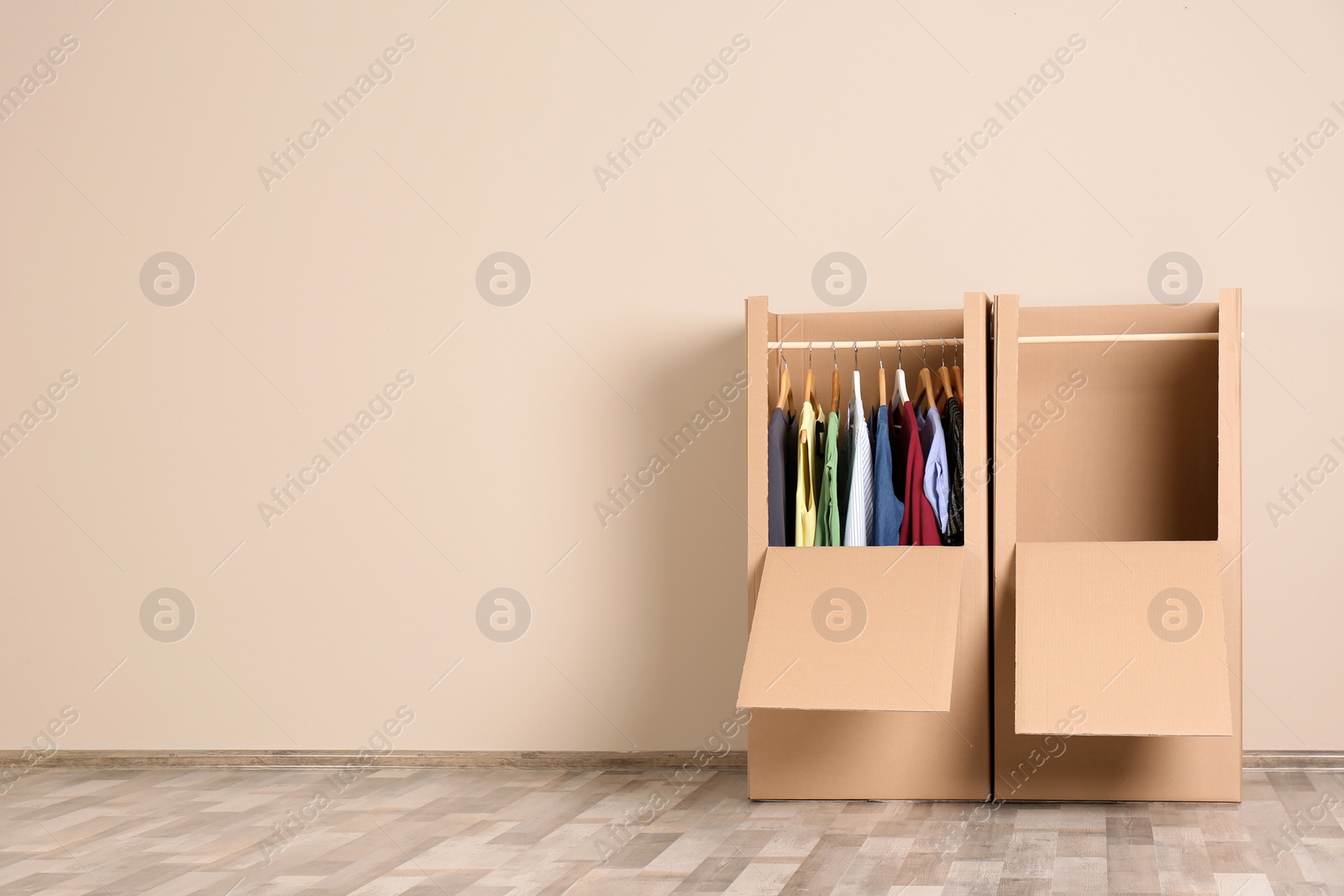 Photo of Wardrobe boxes with clothes against color wall indoors. Space for text