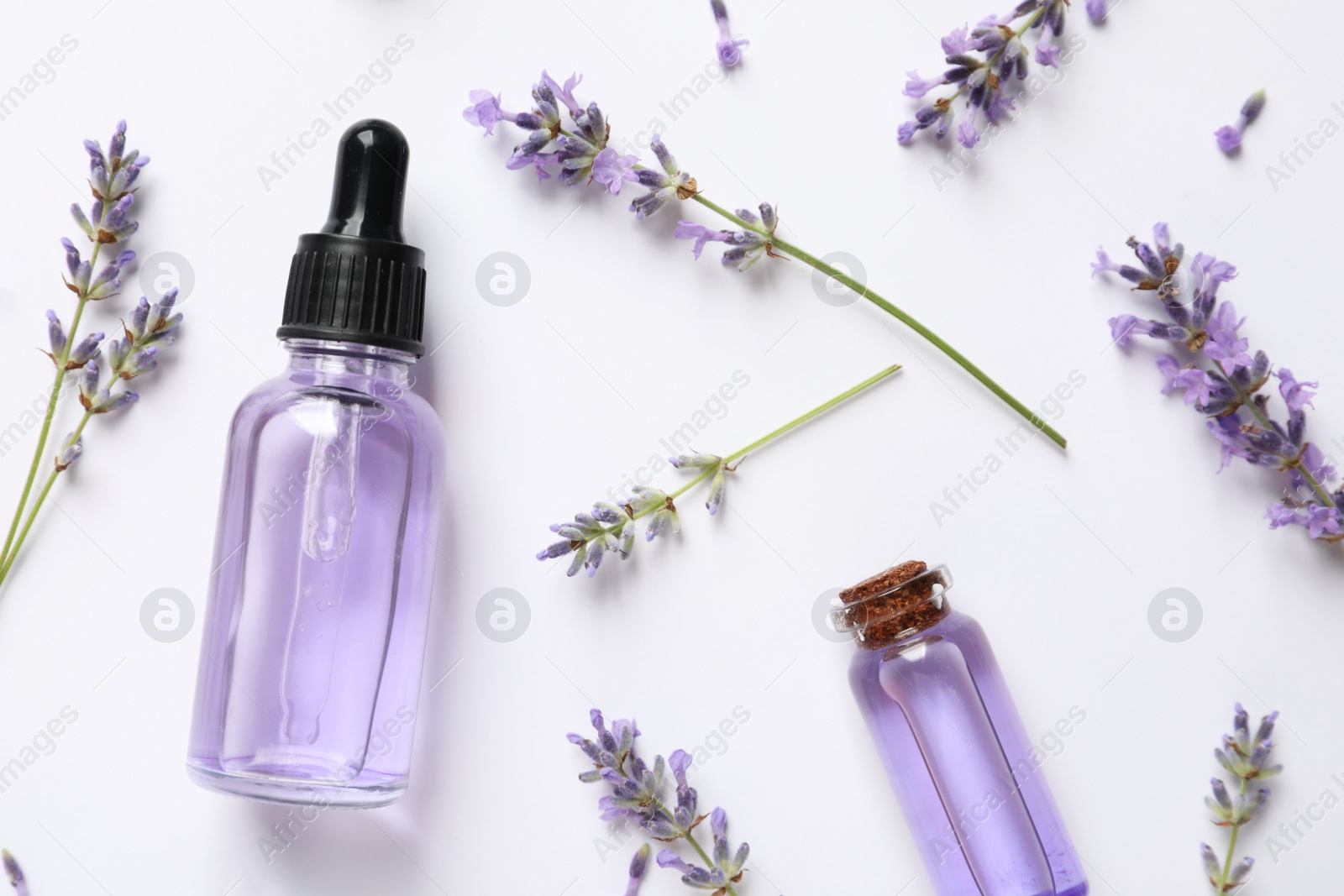 Photo of Natural essential oils and lavender flowers on white background, top view. Cosmetic products