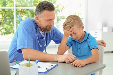 Photo of Male medical assistant consulting child in clinic