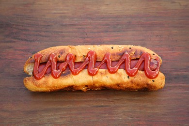 Photo of Fresh tasty hot dog with ketchup on wooden table