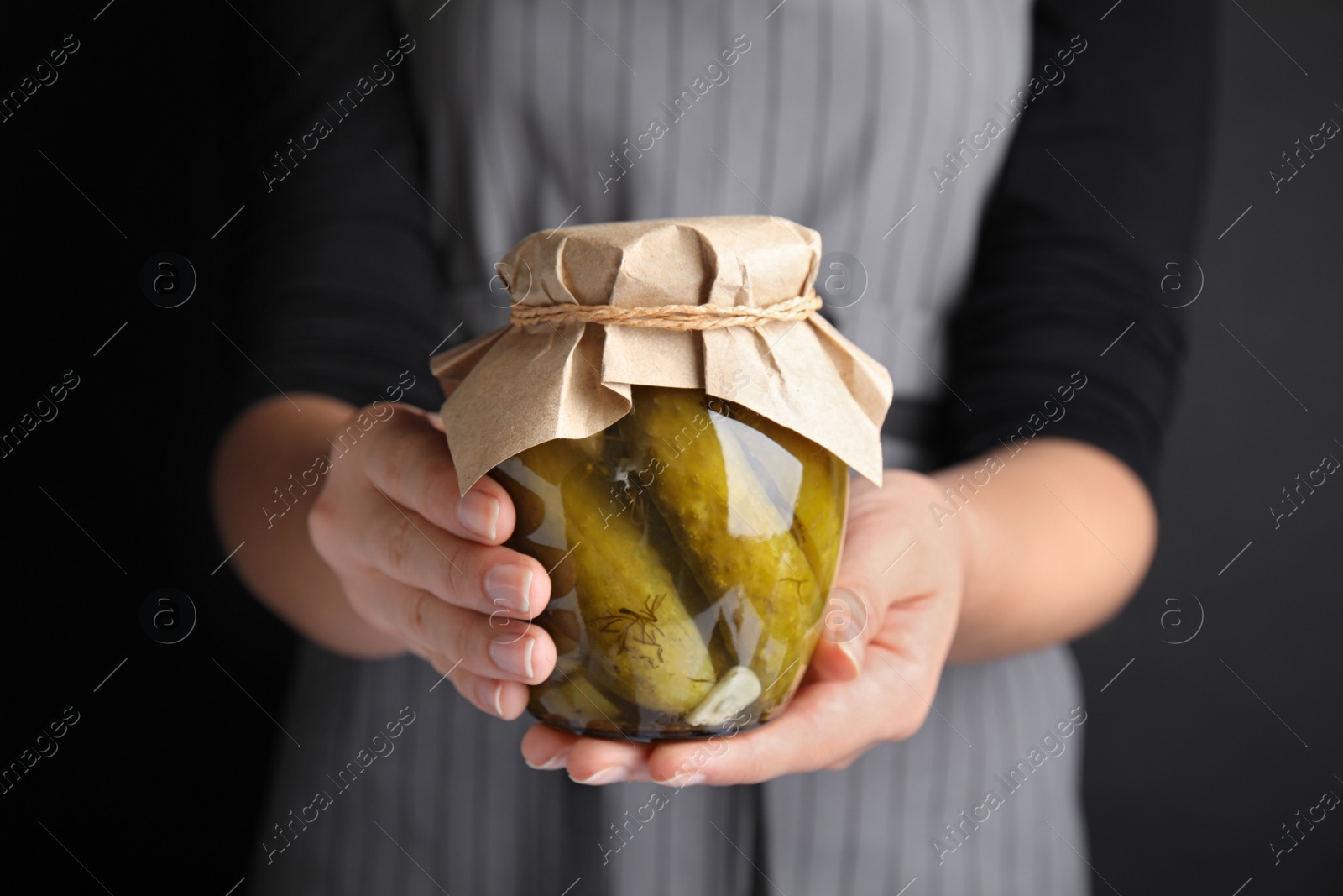 Photo of Woman holding jar of pickled cucumbers, closeup view