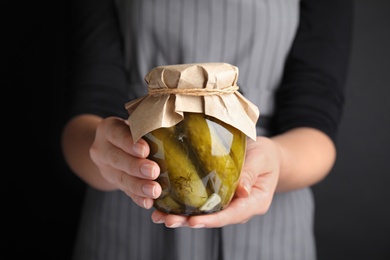 Woman holding jar of pickled cucumbers, closeup view