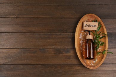 Photo of Card with word Retreat, green branch, cosmetic bottle and sea salt on wooden table, top view. Space for text