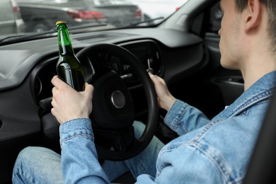 Photo of Man with bottle of beer driving car, closeup. Don't drink and drive concept