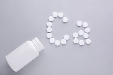 Photo of Open bottle and calcium symbol made of white pills on light grey background, flat lay