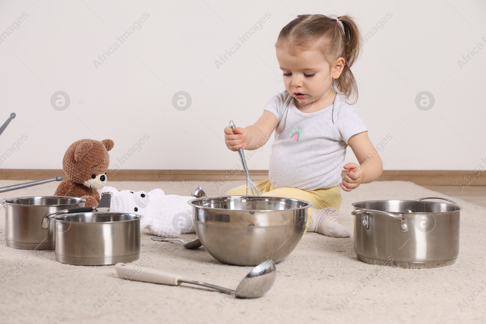 Photo of Cute little girl with cookware at home