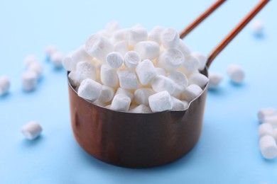 Scoop with delicious marshmallows on light blue background, closeup