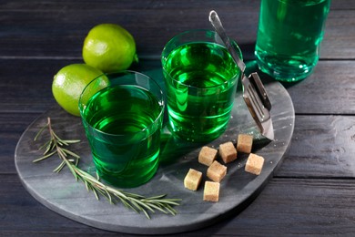 Photo of Absinthe in glasses, rosemary, brown sugar and lime on wooden table. Alcoholic drink