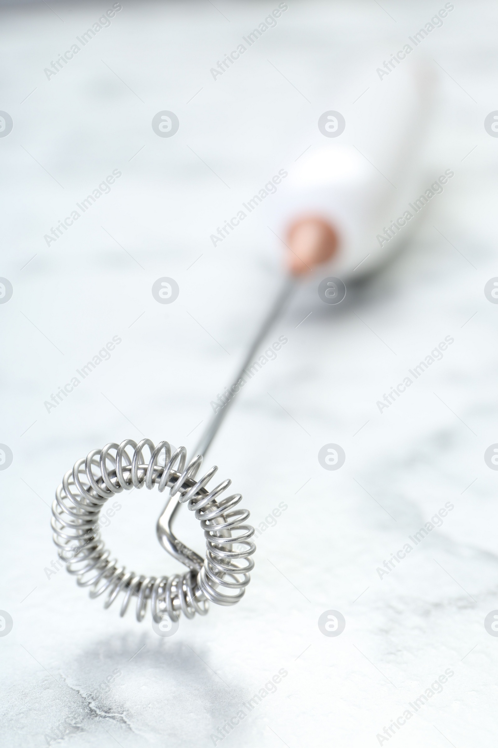 Photo of Milk frother wand on white marble table, closeup