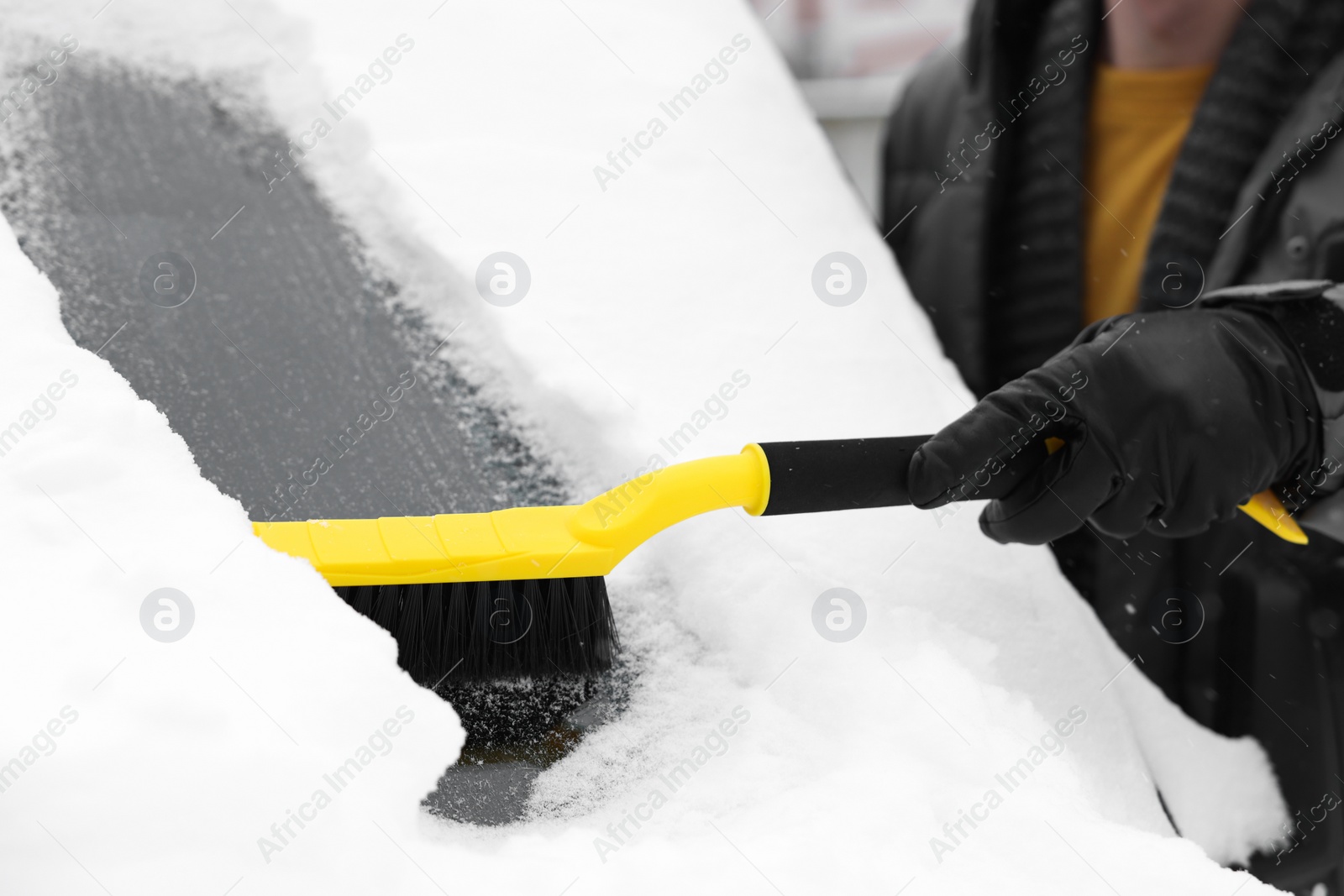 Photo of Man cleaning snow from car windshield outdoors, closeup