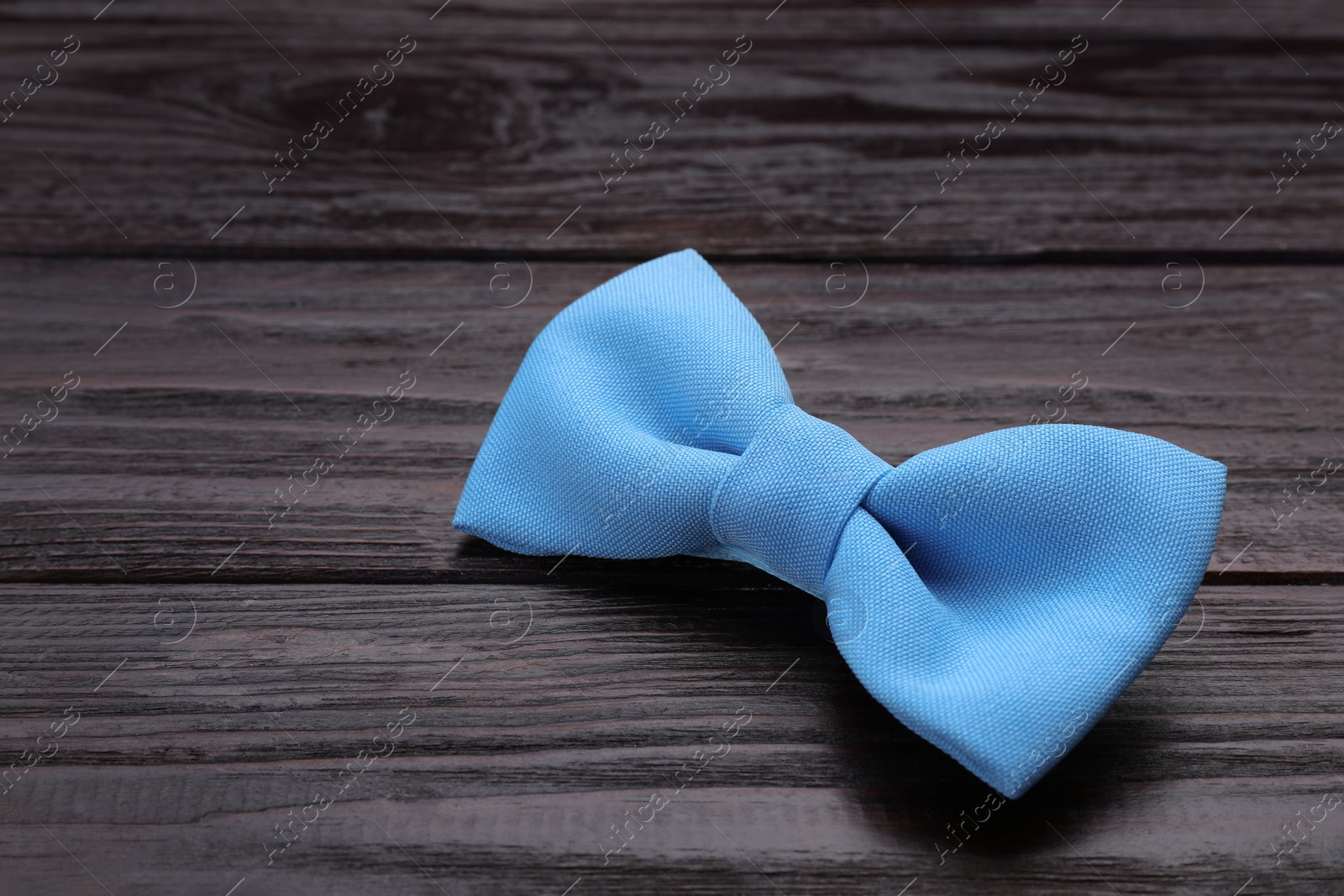 Photo of Stylish light blue bow tie on wooden table. Space for text