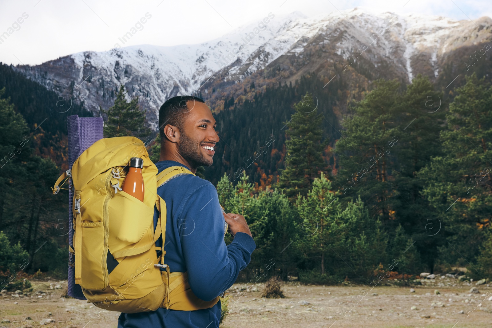 Image of Happy tourist with yellow backpack in mountains