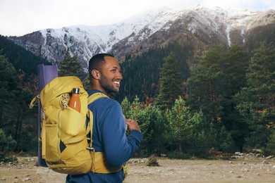 Image of Happy tourist with yellow backpack in mountains