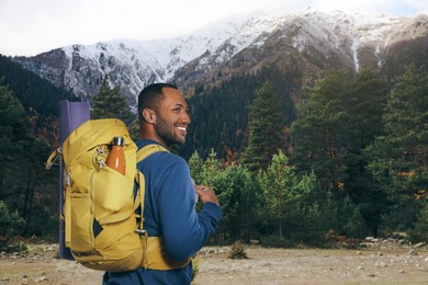 Happy tourist with yellow backpack in mountains