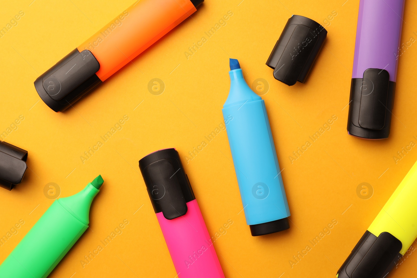 Photo of Bright markers on orange background, flat lay