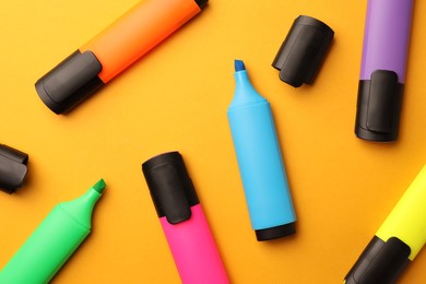 Bright markers on orange background, flat lay