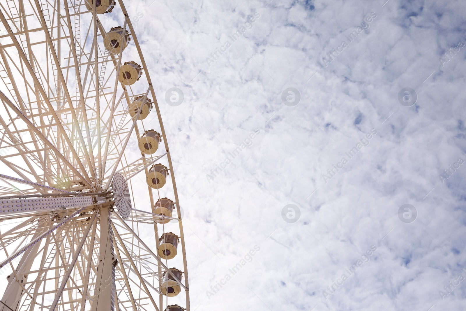 Photo of Beautiful Ferris wheel against cloudy sky, low angle view. Space for text