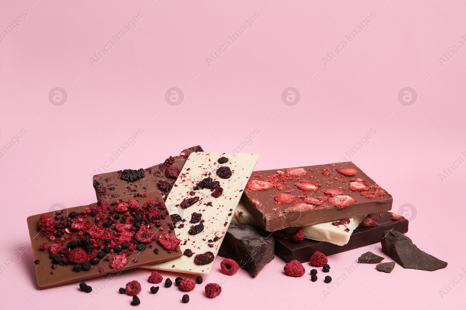Photo of Different chocolate bars with freeze dried fruits on pink background, space for text