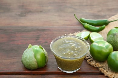 Photo of Tasty salsa sauce and ingredients on wooden table, closeup
