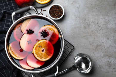 Photo of Delicious mulled wine and ingredients on grey table, flat lay. Space for text