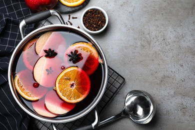 Delicious mulled wine and ingredients on grey table, flat lay. Space for text