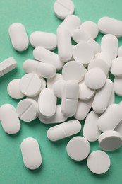 Photo of Pile of white pills on green background, flat lay