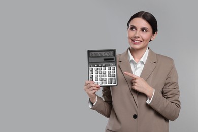 Photo of Smiling accountant with calculator on grey background, space for text