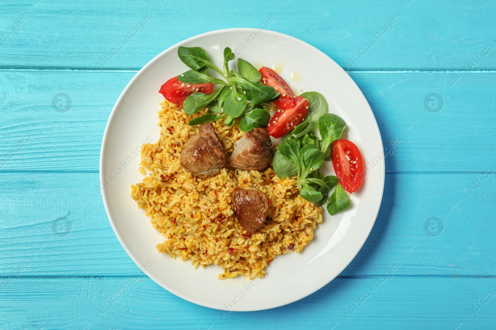 Photo of Plate with delicious rice pilaf and salad on wooden background, top view