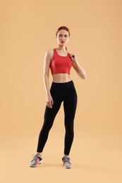 Photo of Young woman in sportswear on beige background